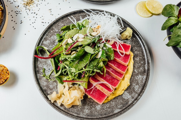 Close de um prato de sushi com legumes frescos na mesa branca