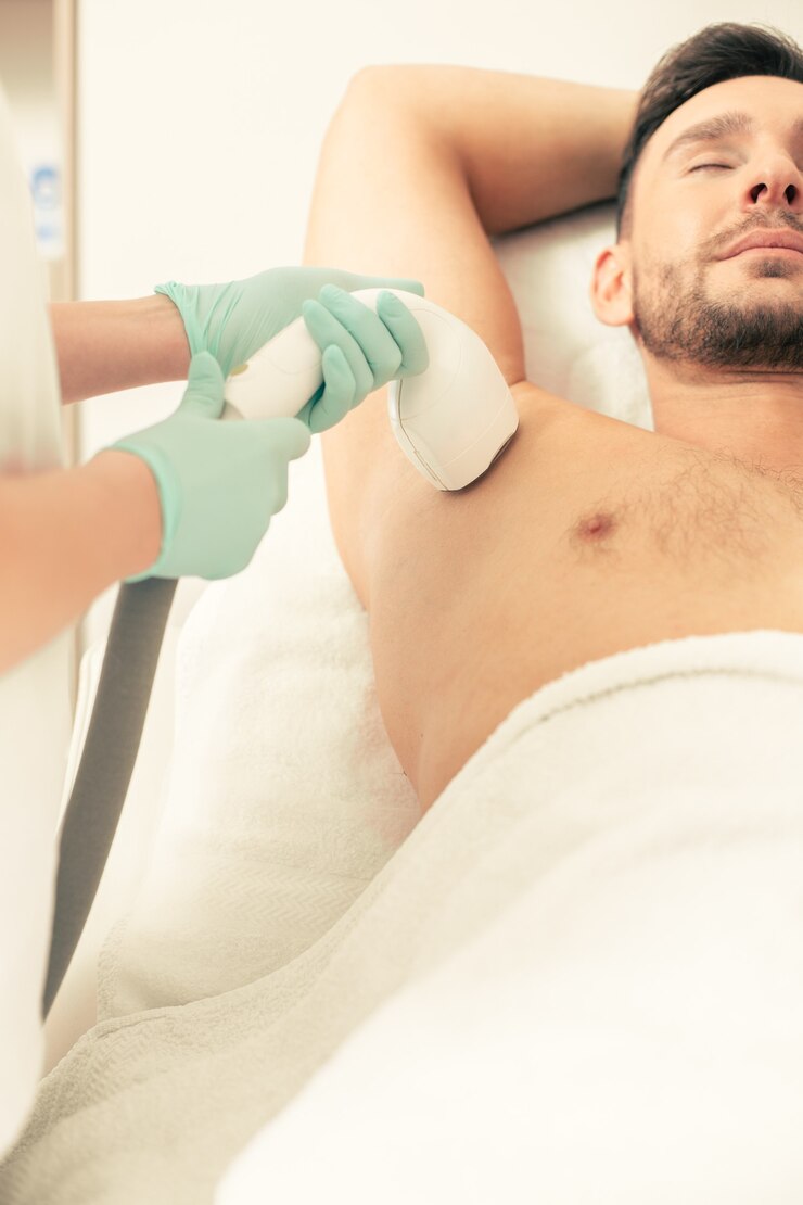 Close de um trabalhador médico em luvas de borracha realizando o procedimento de depilação a laser com sucção a vácuo na axila de um homem