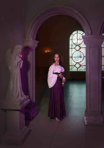 Close de uma bela cigana na sala escura da igreja catedral com pandeiro musical na mão