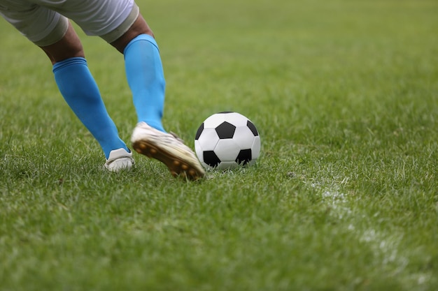 Close de uma bola de futebol com um jogador chutando a bola