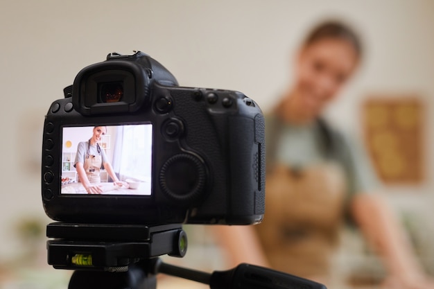 Close de uma câmera de vídeo com uma mulher na tela. Blogueira de culinária criando um conteúdo