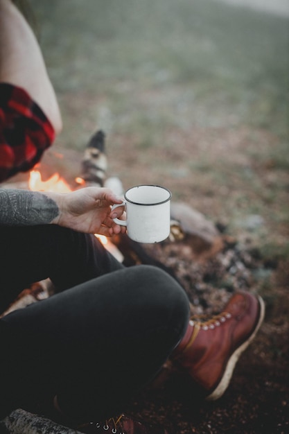 Close de uma caneca esmaltada hipster com chá na mão do turista