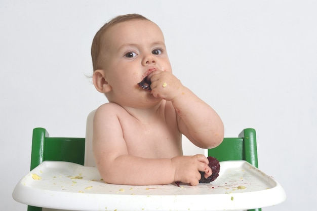 Close de uma criança comendo ameixa no fundo branco