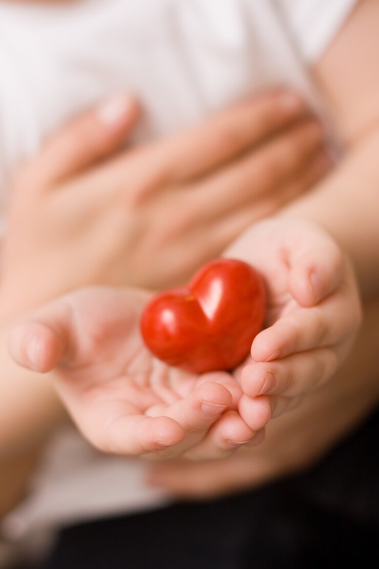 close de uma criança nos braços de uma mãe com um lindo coração vermelho nas mãos