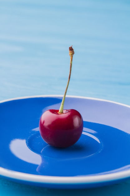 Close de uma doce cereja madura no prato azul