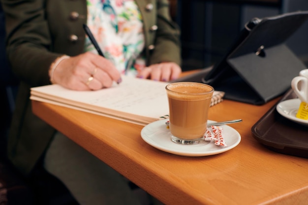 Close de uma empresária trabalhando na cafeteria com um tablet e um notebook