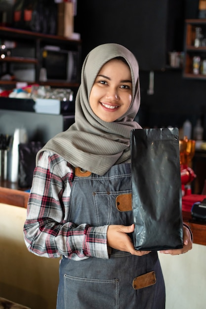 Close de uma garçonete sorrindo, segurando um bolso antes de entregar ao cliente