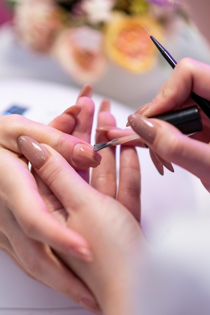 Close de uma garota fazendo manicure em um salão de beleza Cuidados com as unhas Manicure aplica verniz na unha Manicure de hardware revelada Procedimento cosmético