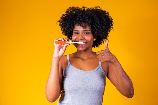 Close de uma jovem afro escovando os dentes com uma escova de dentes