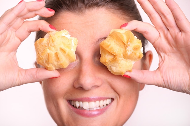 Close de uma jovem cobrindo os olhos com bolinhas de creme sobre o branco