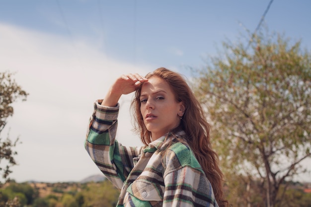 Foto close de uma jovem modelo se protegendo do sol enquanto olha para a câmera