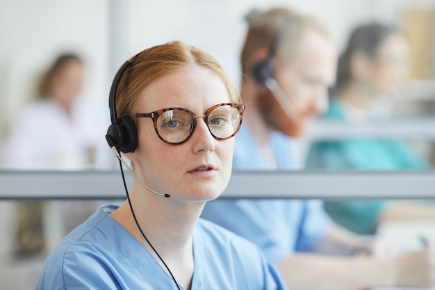 Close de uma jovem operadora de óculos e fone de ouvido, olhando enquanto fala ao telefone