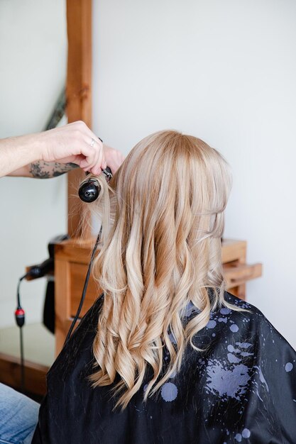 Close de uma mão masculina cortando o cabelo com uma tesoura