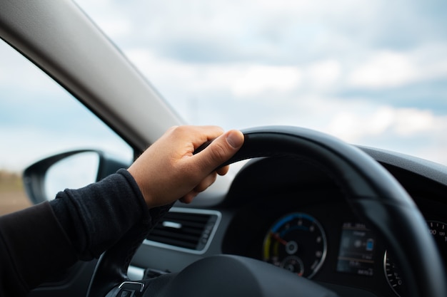 Close de uma mão masculina segurando o volante