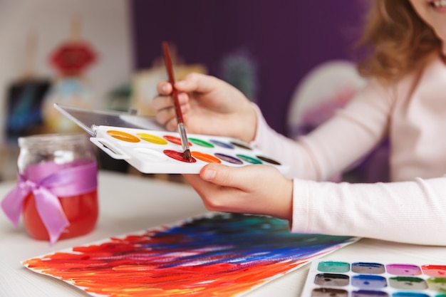 Close de uma menina pintando um quadro na mesa em casa