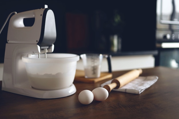 Foto close de uma mesa em uma cozinha caseira com uma batedeira e produtos para sobremesas. preparando-se para a preparação de alimentos.