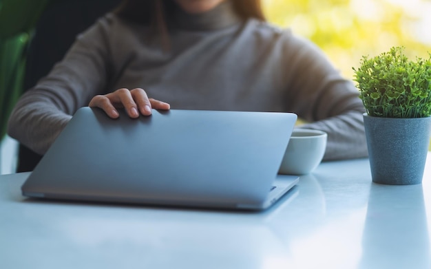 Close de uma mulher abrindo um laptop se preparando para o trabalho no escritório