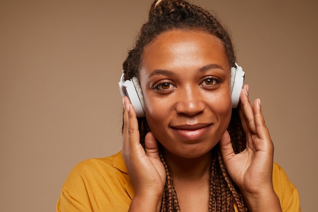 Close de uma mulher africana usando fones de ouvido sem fio e ouvindo música