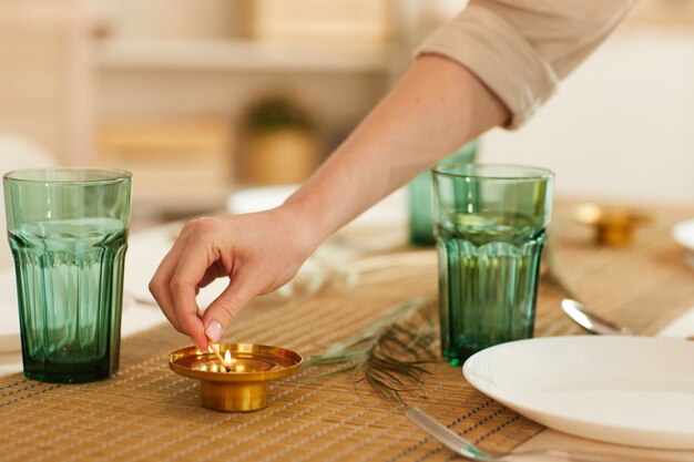 Close de uma mulher irreconhecível acendendo uma vela enquanto servia a mesa para os convidados