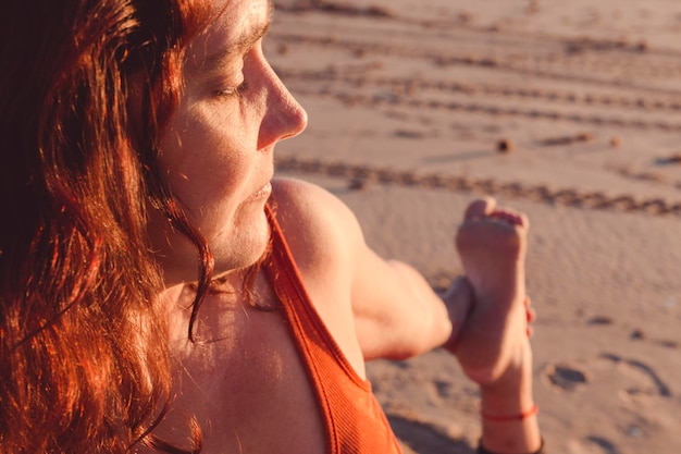 Close de uma mulher que se estende na areia da praia