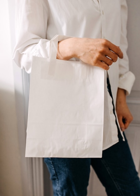 Close de uma mulher segurando uma sacola de papel em branco