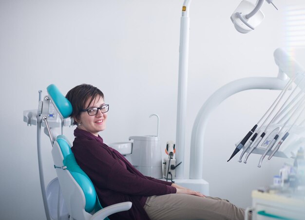 Close de uma paciente no dentista esperando para ser verificada com a médica ao fundo