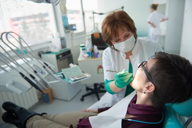 Close de uma paciente no dentista esperando para ser verificada com a médica ao fundo