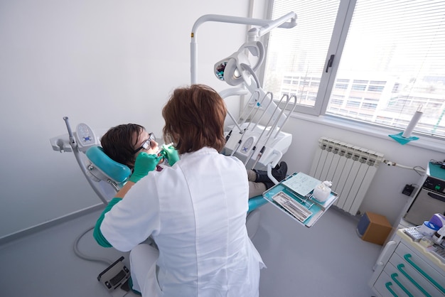 Close de uma paciente no dentista esperando para ser verificada com a médica ao fundo