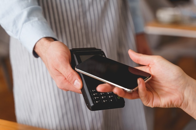 Close de uma senhora usando smartphone para pagar um pedido no restaurante