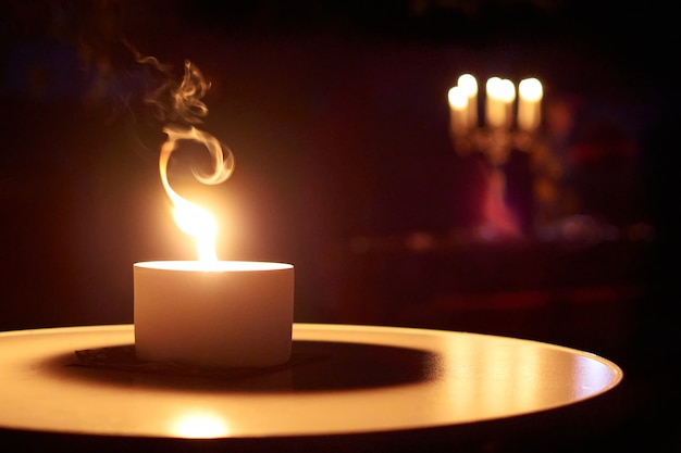 Close de uma vela acesa em uma mesa no escuro