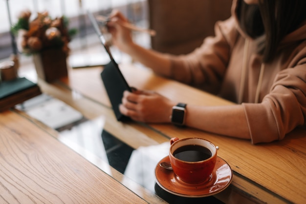 Close de uma xícara de café escuro sobre a mesa de um café