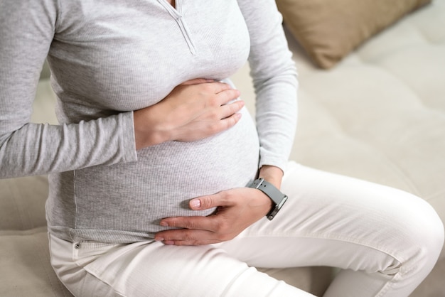 Close do abdômen de grávida, barriga, gravidez saudável, mulher grávida em jaqueta cinza