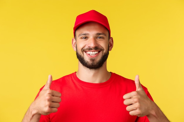 Close do entregador amigável e sorridente com boné de uniforme vermelho e camiseta fornece o melhor frete expresso ...