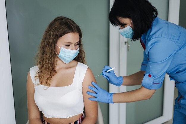 Close do médico em luvas de proteção segurando uma seringa e usando algodão antes de fazer a injeção para