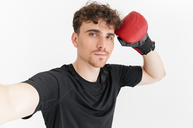 Close do retrato de um homem atraente e esportivo em uma camiseta, olhando para a frente e tirando uma selfie