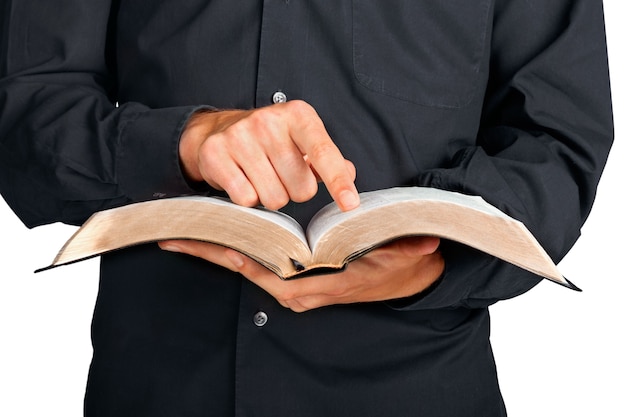 Close em um padre segurando uma bíblia e apontando o dedo