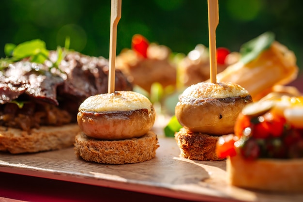 Close em uma variedade de tapas espanholas com diferentes coberturas na placa de madeira