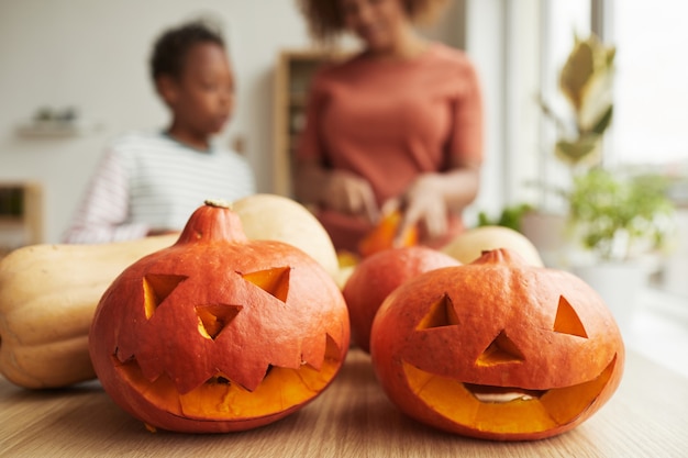 Foto close horizontal de abóboras que a mãe e o filho esculpiram para a festa de halloween em casa