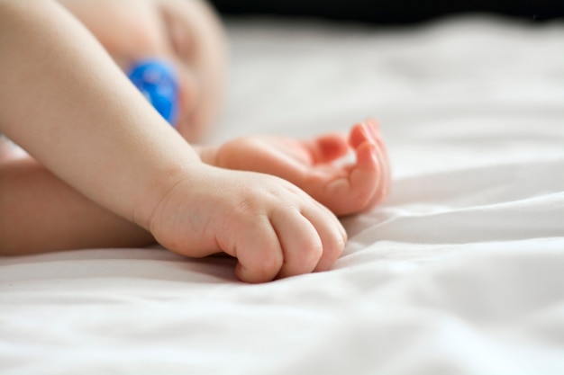 Foto close nas mãos de um bebê dormindo na cama