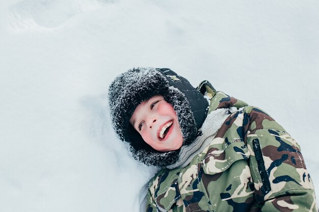 Close no rosto de um garoto rindo deitado na neve