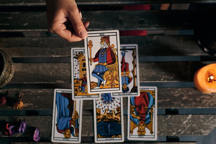 Close-up de un adivino mostrando algunas cartas del tarot en una mesa de madera