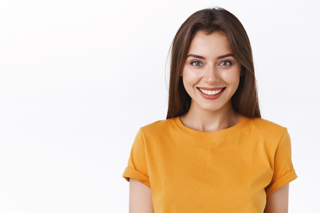 Close-up atraente feliz sorridente mulher morena em t-shirt amarela ansiosa por evento emocionante, sorrindo alegremente expressando positividade e entusiasmo, feliz por participar de interessante campanha promocional