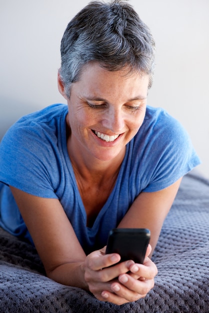 Close-up atraente mulher madura sorrindo e usando telefone celular