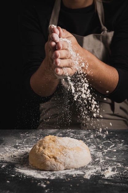 Close-up baker extendiendo harina sobre la masa