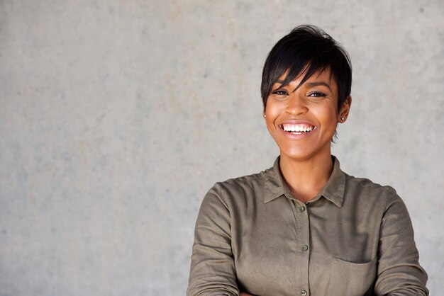 Close-up bela jovem negra sorrindo contra parede cinza