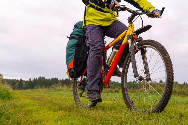 Foto close-up de una bicicleta turística con una alforja cabalgando por el campo en una tarde nublada en el campo