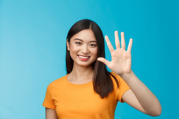 Close-up bonita amigável alegre mulher asiática levantar palm show número cinco, quinto, sorrindo alegremente, descrever quantas coisas precisam, ficar de fundo azul otimista, comunicar. Copie o espaço