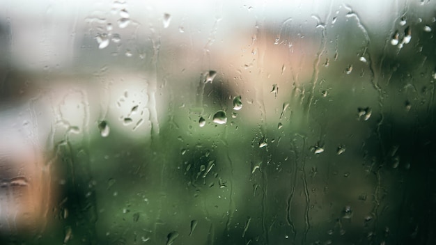 Close-up caindo água da chuva e bolhas no vidro da janela molhada