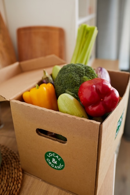 Close-up de caja de cartón con verduras frescas en la mesa que se entrega a casa