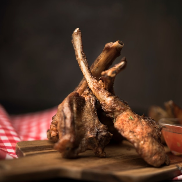 Close-up chuletas de cordero sobre tabla de madera con salsa